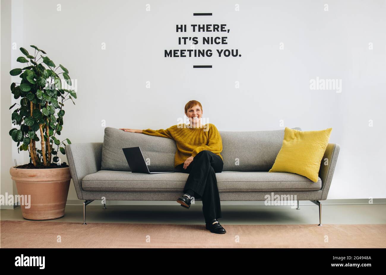 Positive female sitting on sofa in office lobby. Confident entrepreneur sitting in lobby. Stock Photo