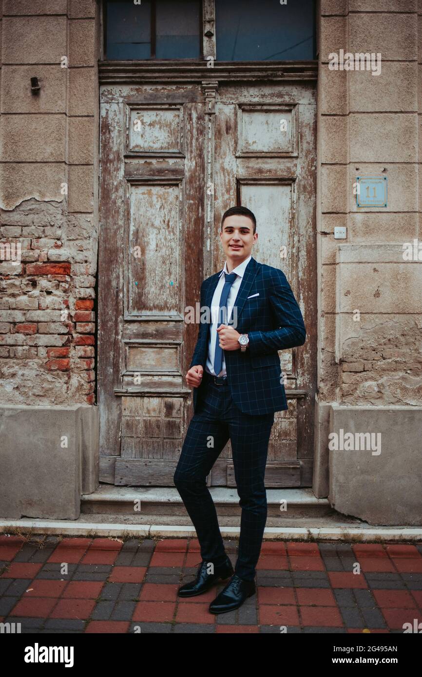 Caucasian young businessman in a suit and tie posing against the door ...