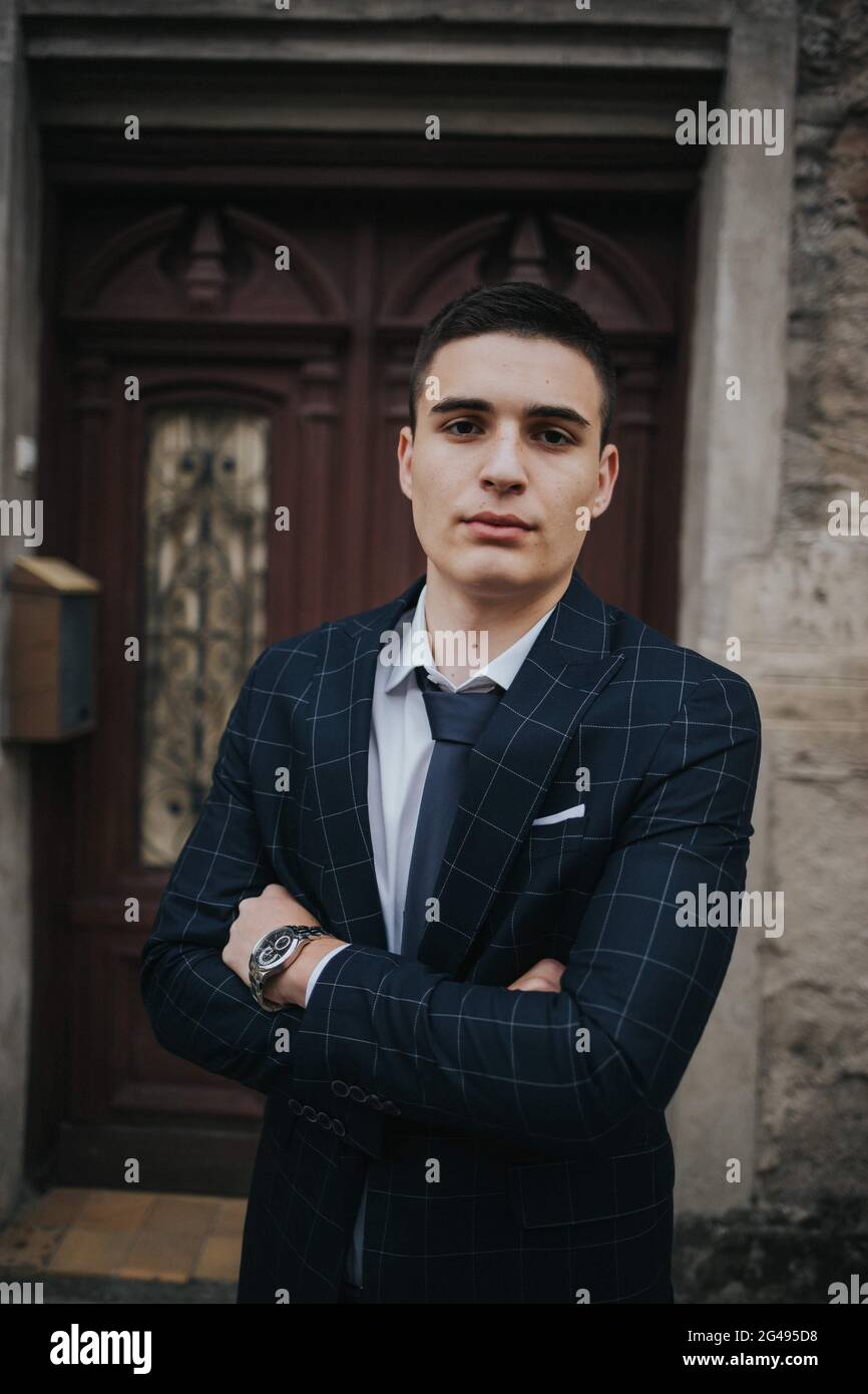 Caucasian young businessman in a suit and tie posing against the door ...