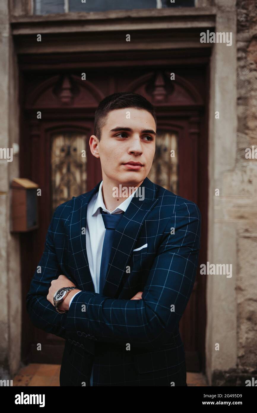 Caucasian young businessman in a suit and tie posing against the door ...