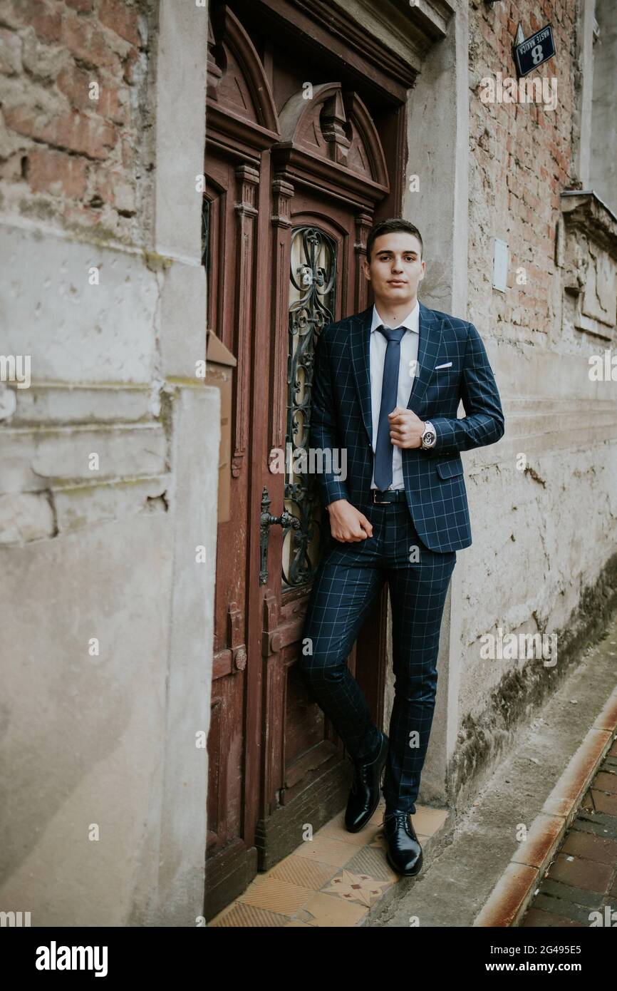 Caucasian young businessman in a suit and tie posing against the door ...