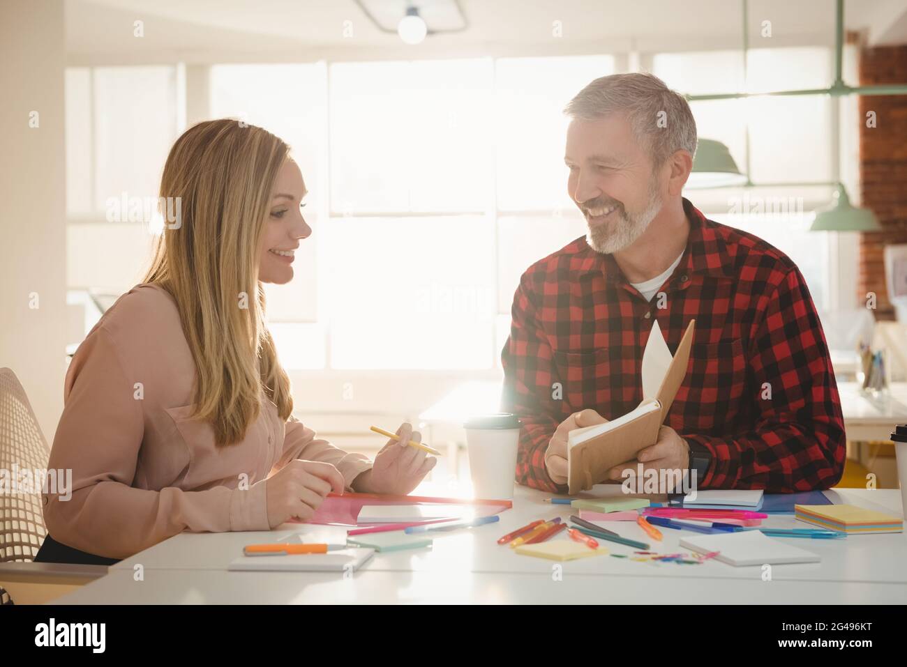 Smiling executives discussing over diary Stock Photo
