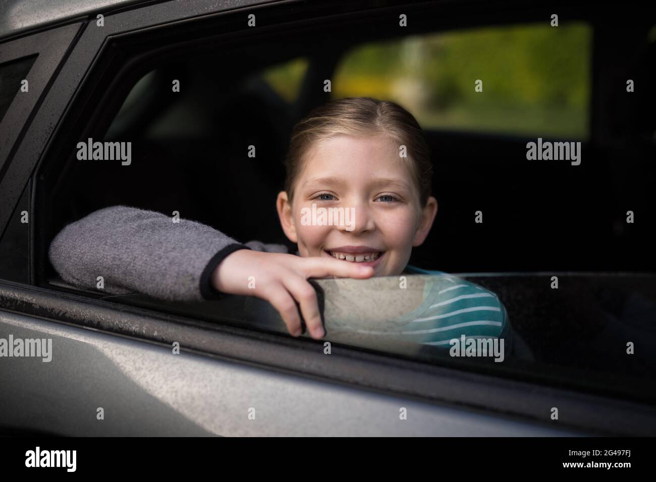 Smiling teenage girl looking through car window Stock Photo