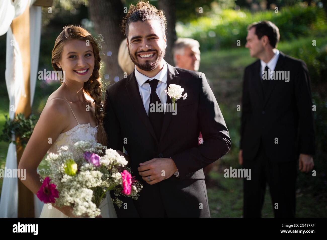 Happy bride and groom standing in park Stock Photo - Alamy