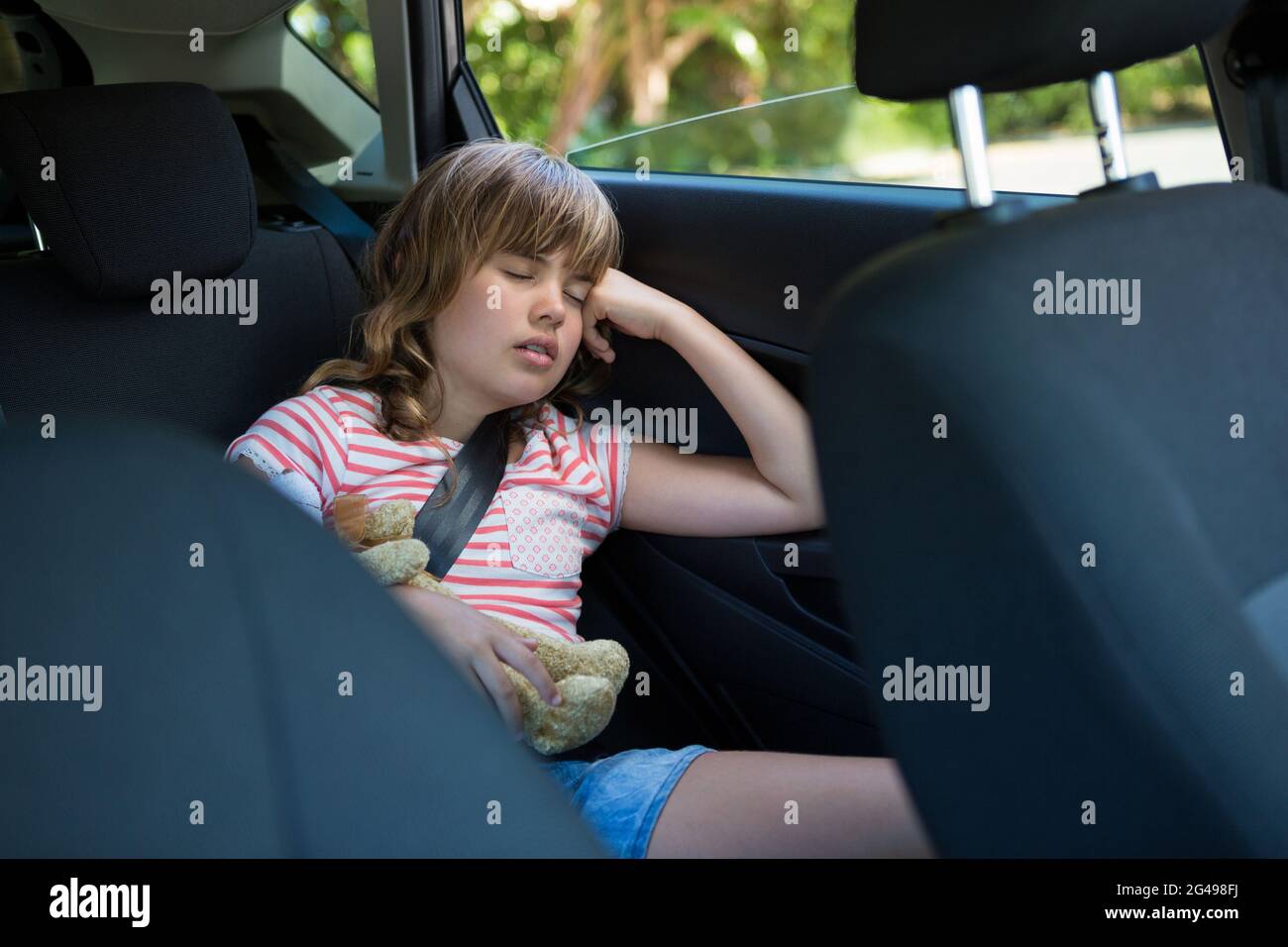 Teenage girl sleeping in the back seat of car Stock Photo