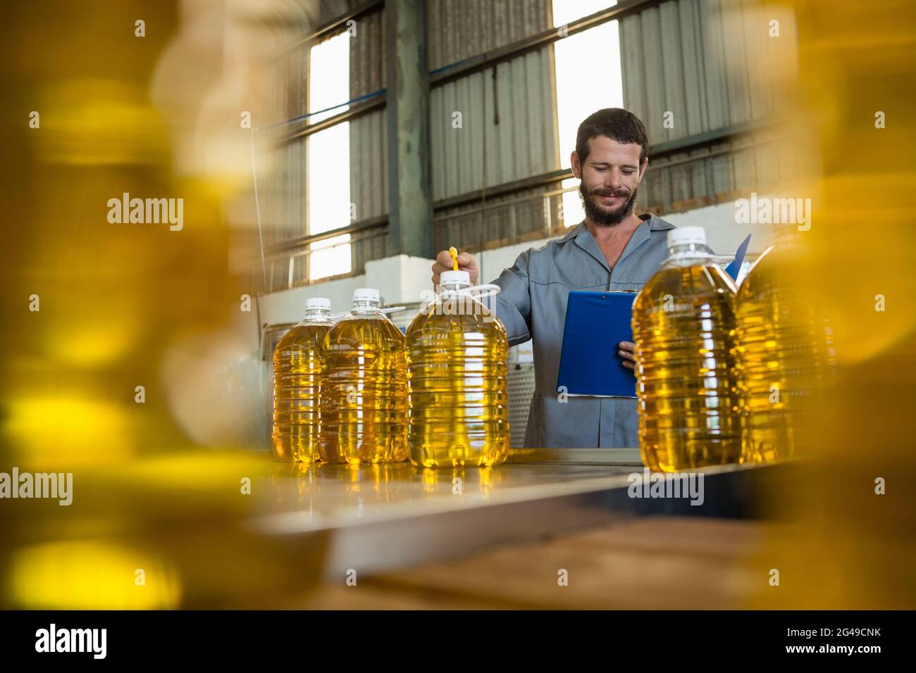 Worker writing on clipboard in olive factory Stock Photo - Alamy