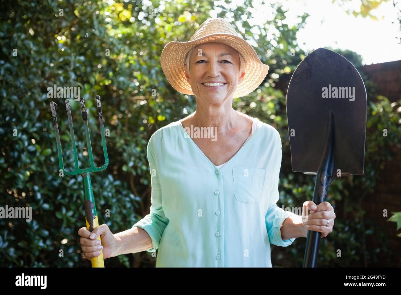 Portrait of smiling senior woman holding garden fork and shovel Stock ...