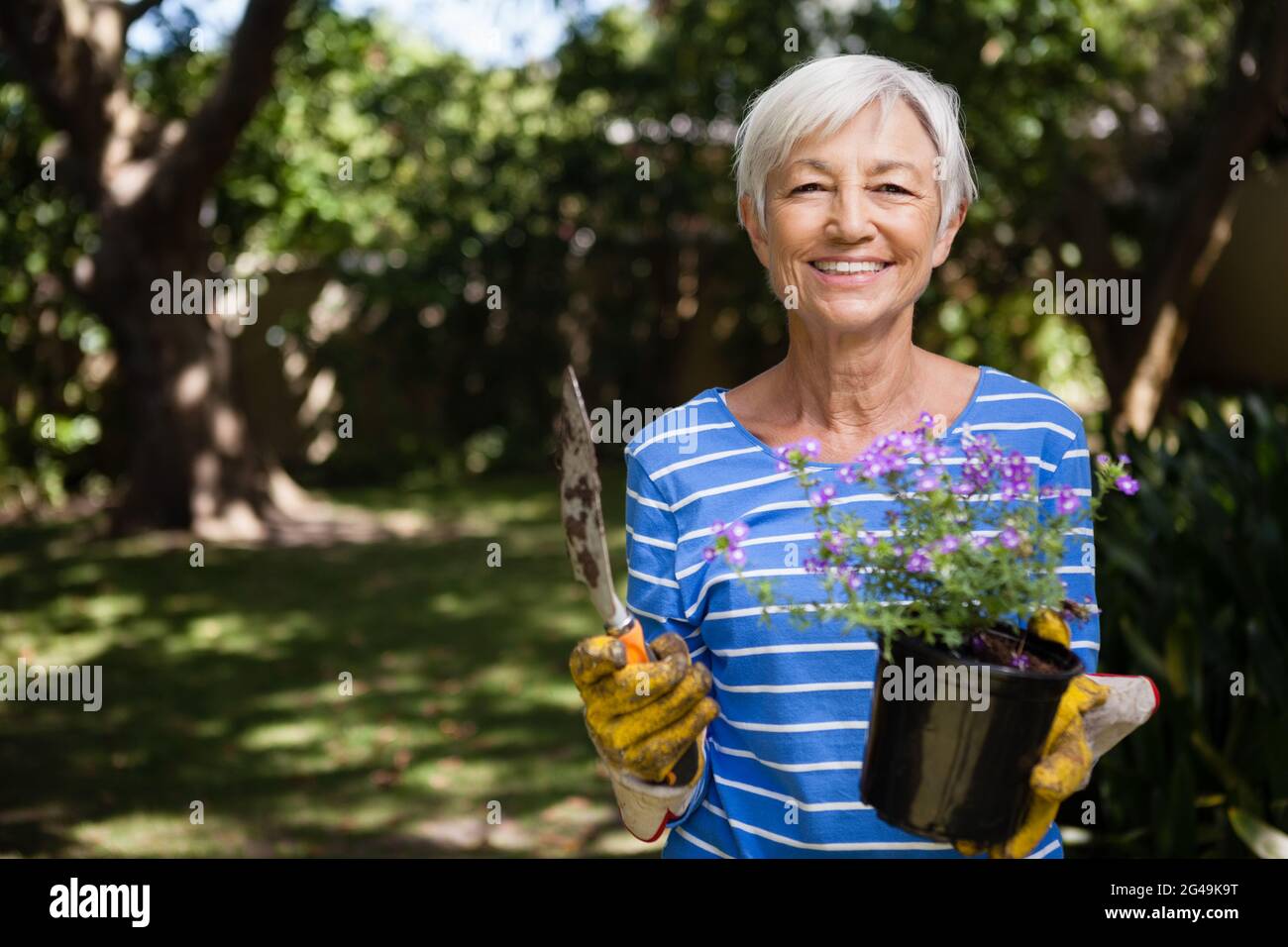 Portrait of senior woman holding potted plant and trowel Stock Photo ...