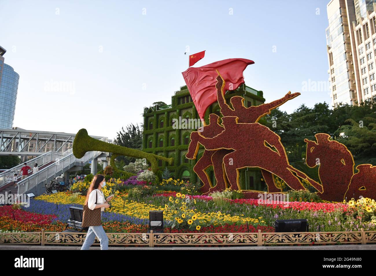 Beijing, China. 19th June, 2021. A woman walks past flower decorations set up along Chang'an Avenue in Beijing, capital of China, June 19, 2021. Credit: Chen Zhonghao/Xinhua/Alamy Live News Stock Photo