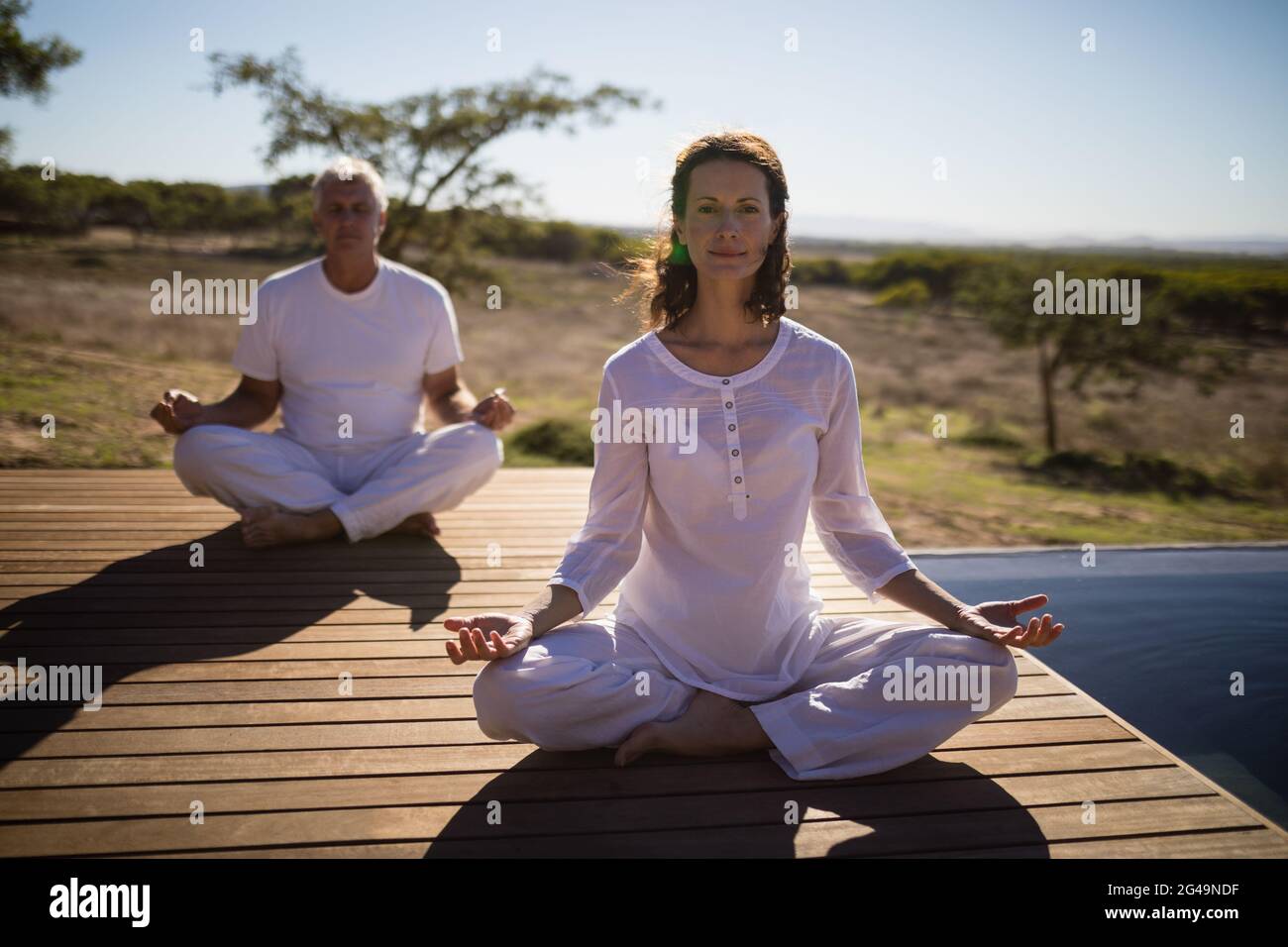 Portrait of couple practicing yoga on wooden plank Stock Photo