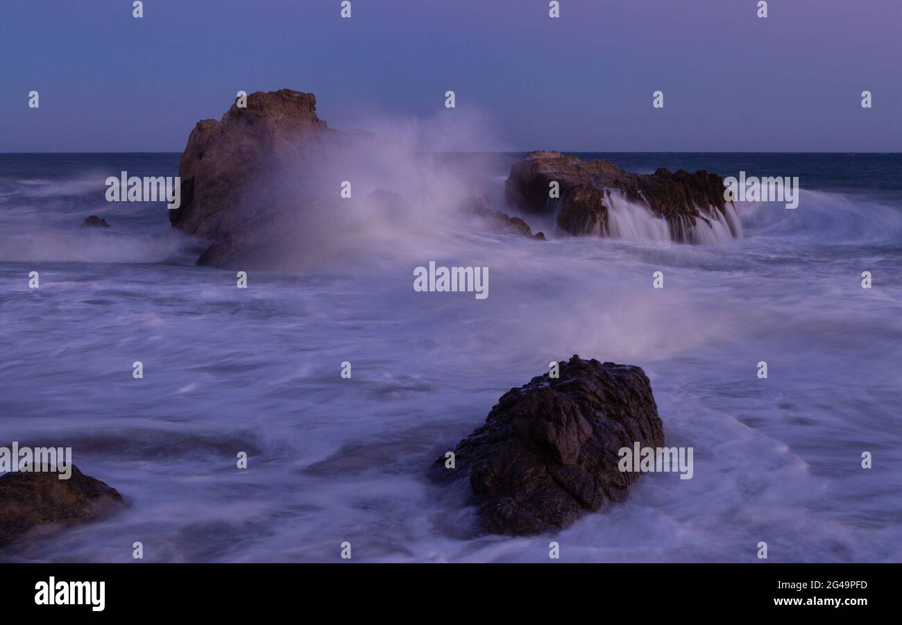 Waves crashing along the beach in Leo Carrillo State park at sunset Stock Photo