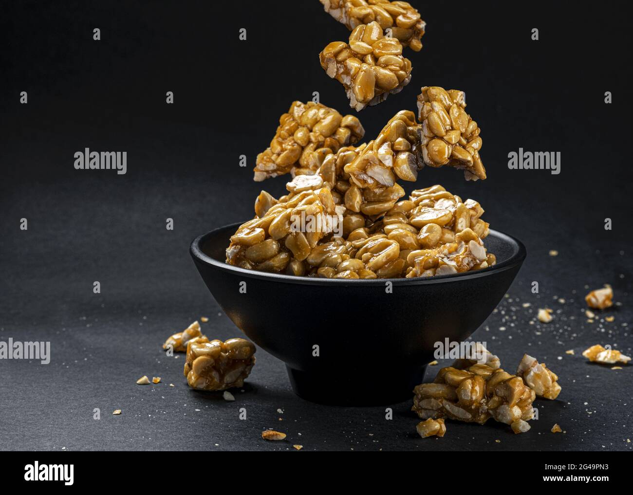 Peanut kozinaki falling in bowl on black background Stock Photo