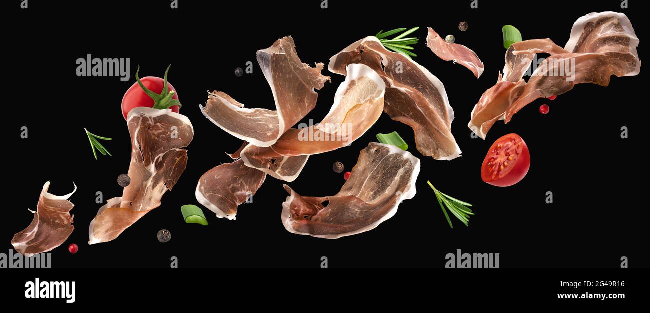 Falling jamon slices, iberian ham isolated on black background Stock Photo