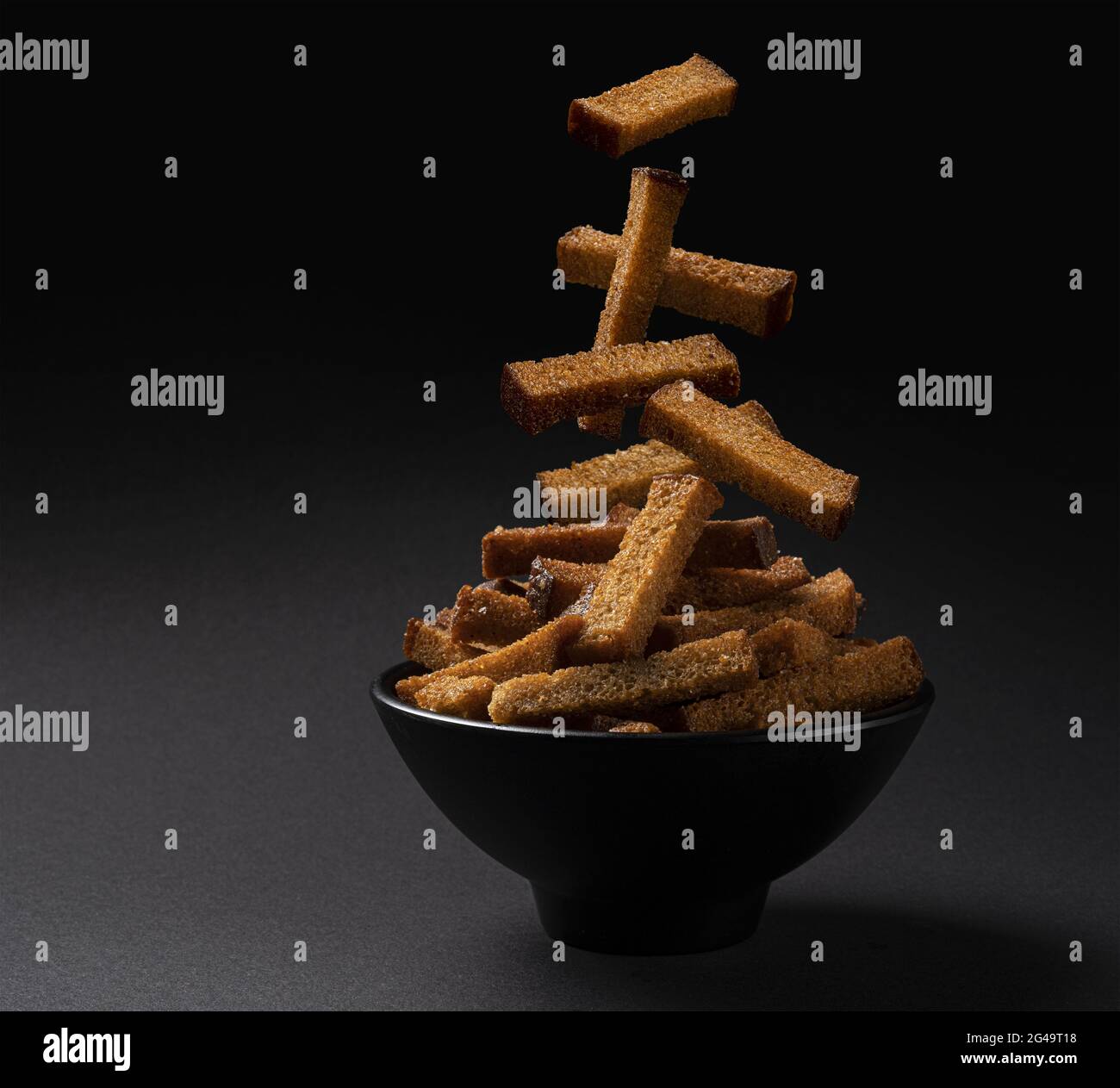 Falling rye bread croutons on black background Stock Photo
