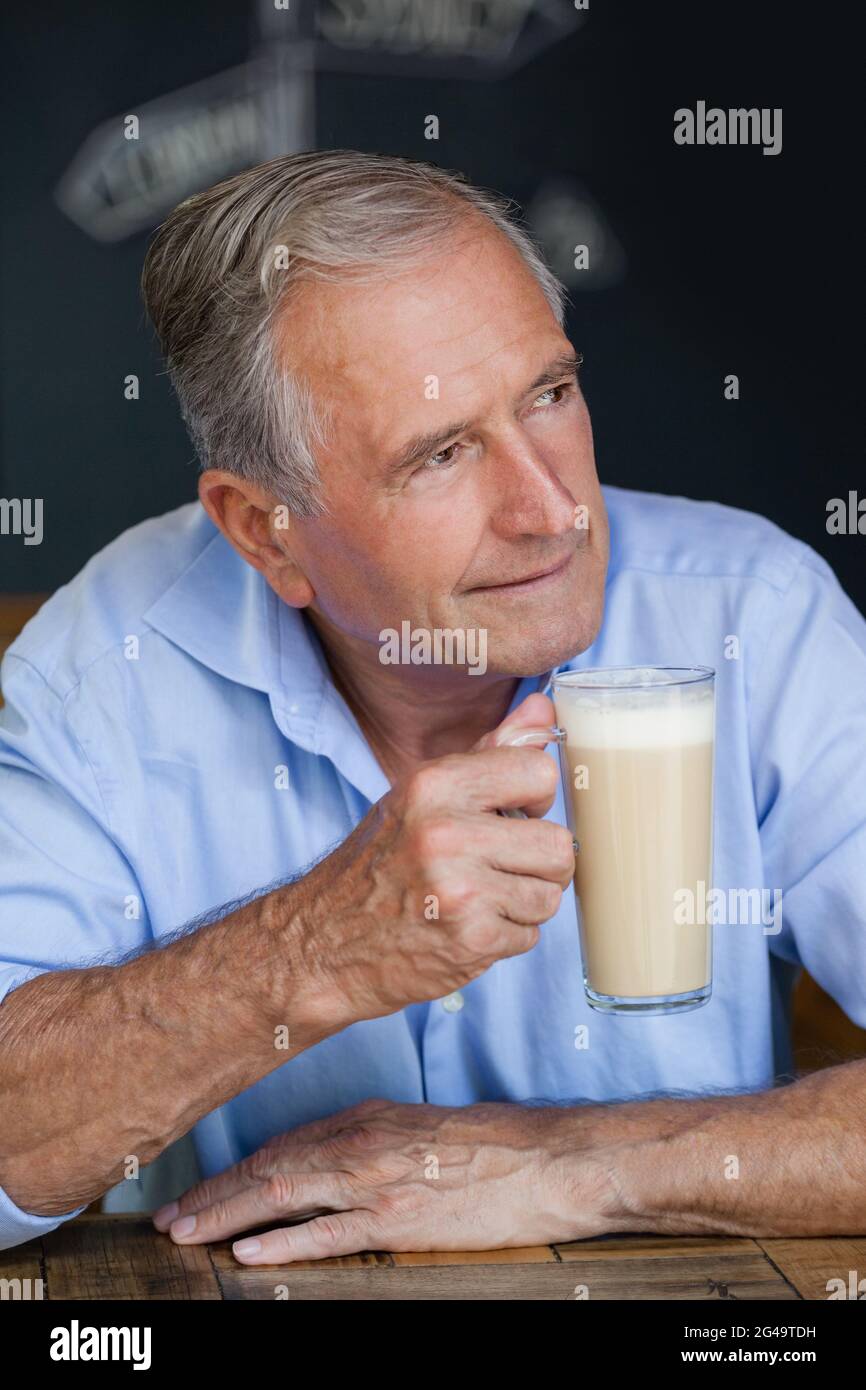 Senior thoughtful man looking away while holding cold coffee Stock Photo