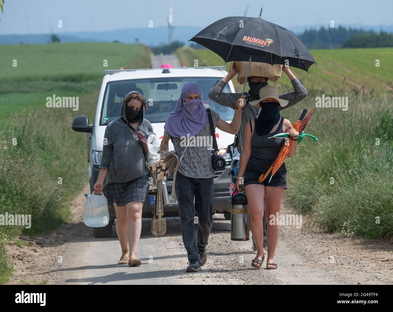 Dannenrod, Germany. 15th June, 2021. On their way to a blockade action, activists drag canisters of drinking water and thermoses of coffee along a dirt road near Dannenrod in Hesse. The further construction of the autobahn has also led to deep divisions among the residents of the small village of Dannenrod. (to dpa: 'Permanent quarrel about A49 burdens villages - 'The anger could never fade away') Credit: Boris Roessler/dpa/Alamy Live News Stock Photo