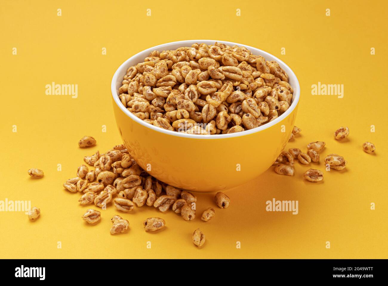Puffed wheat cereal isolated on yellow background Stock Photo