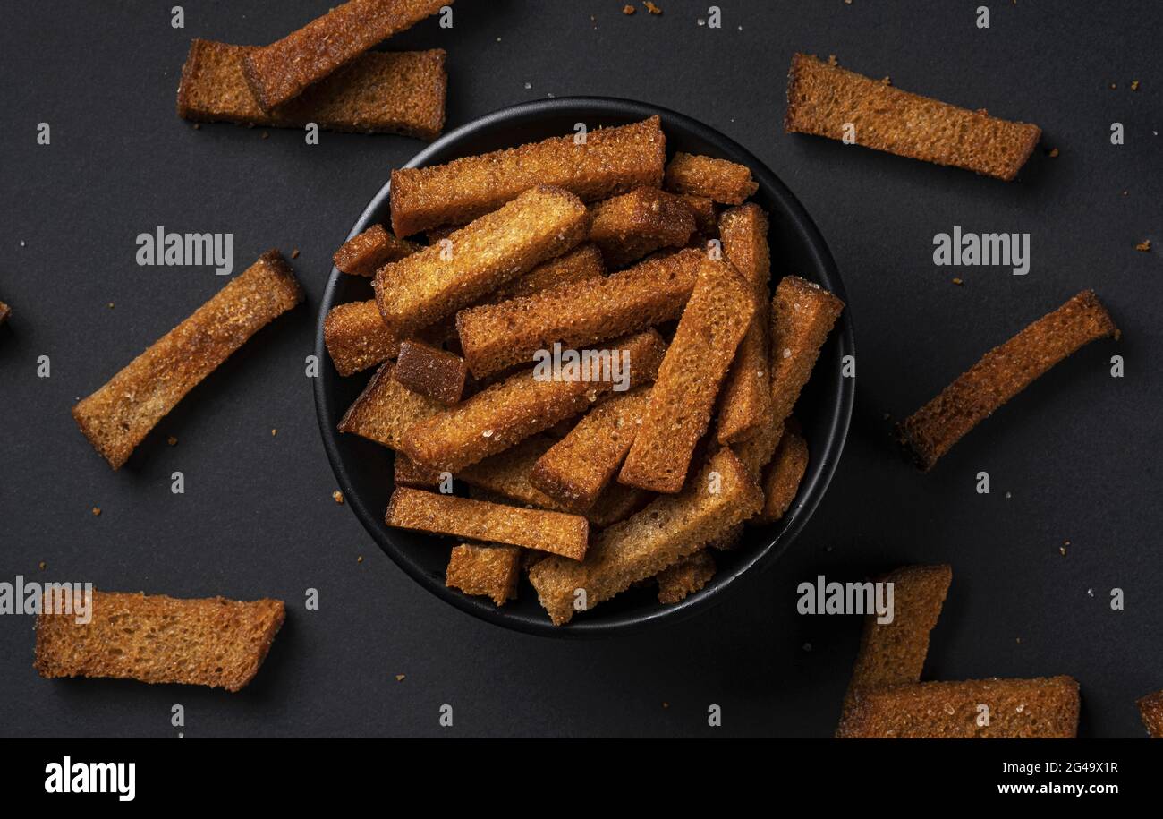 Rye bread croutons on black background, top view Stock Photo