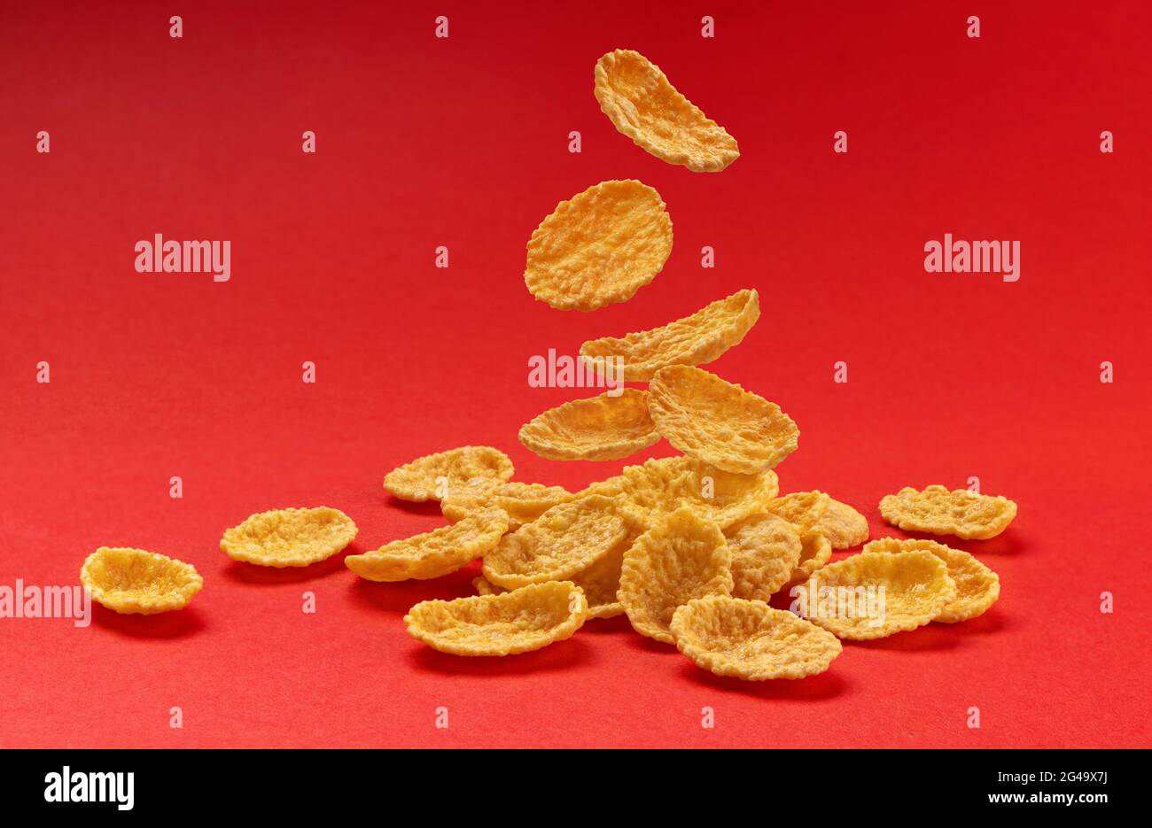 Falling corn flakes isolated on red color background, full depth of field Stock Photo