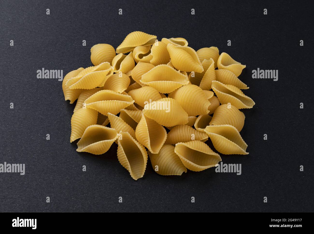 Conchiglie rigate. Raw striped shell pasta on black background Stock Photo