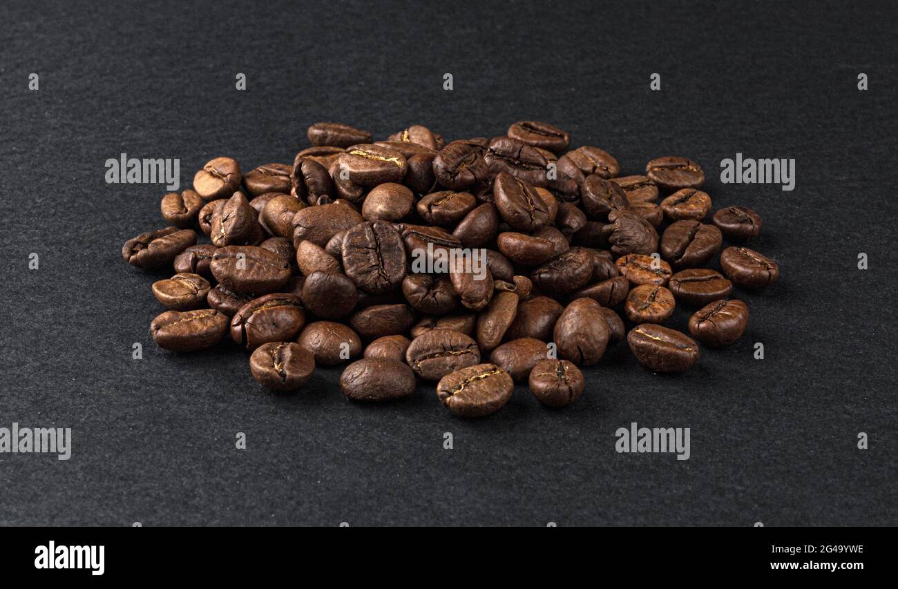 Heap of roasted coffee beans on black background Stock Photo - Alamy