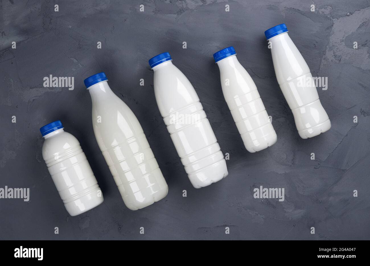 Collection of milk bottles on gray stone background, top view Stock