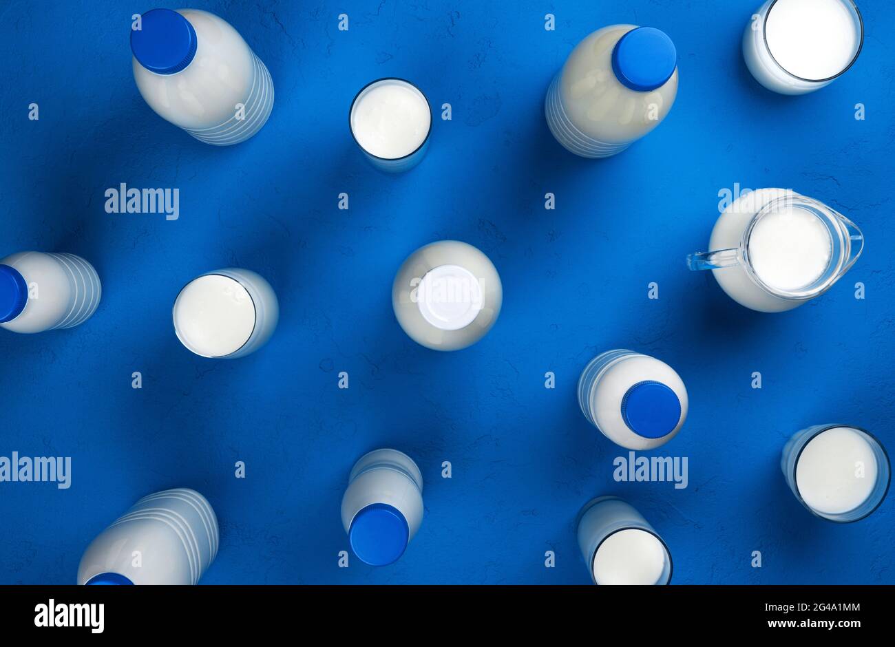Collection of bottles and glasses with milk on blue background, top