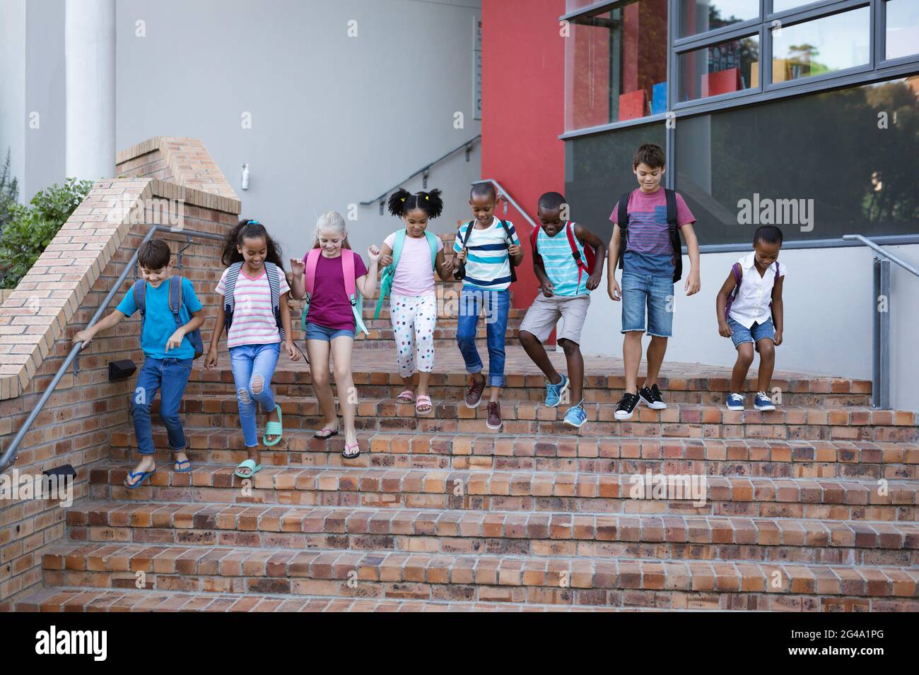 Group of diverse students with backpacks walking down the stairs ...