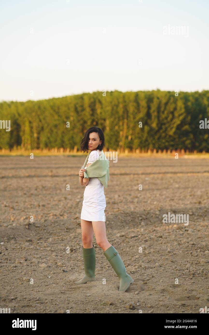 Asian woman, walking in the countryside, wearing a white dress and green wellies. Stock Photo