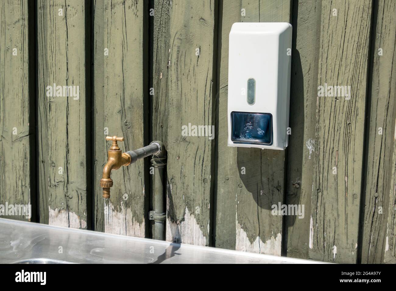 Ry, Denmark - June 16 2021: Old brass faucet and an alcohol dispenser over a sink Stock Photo