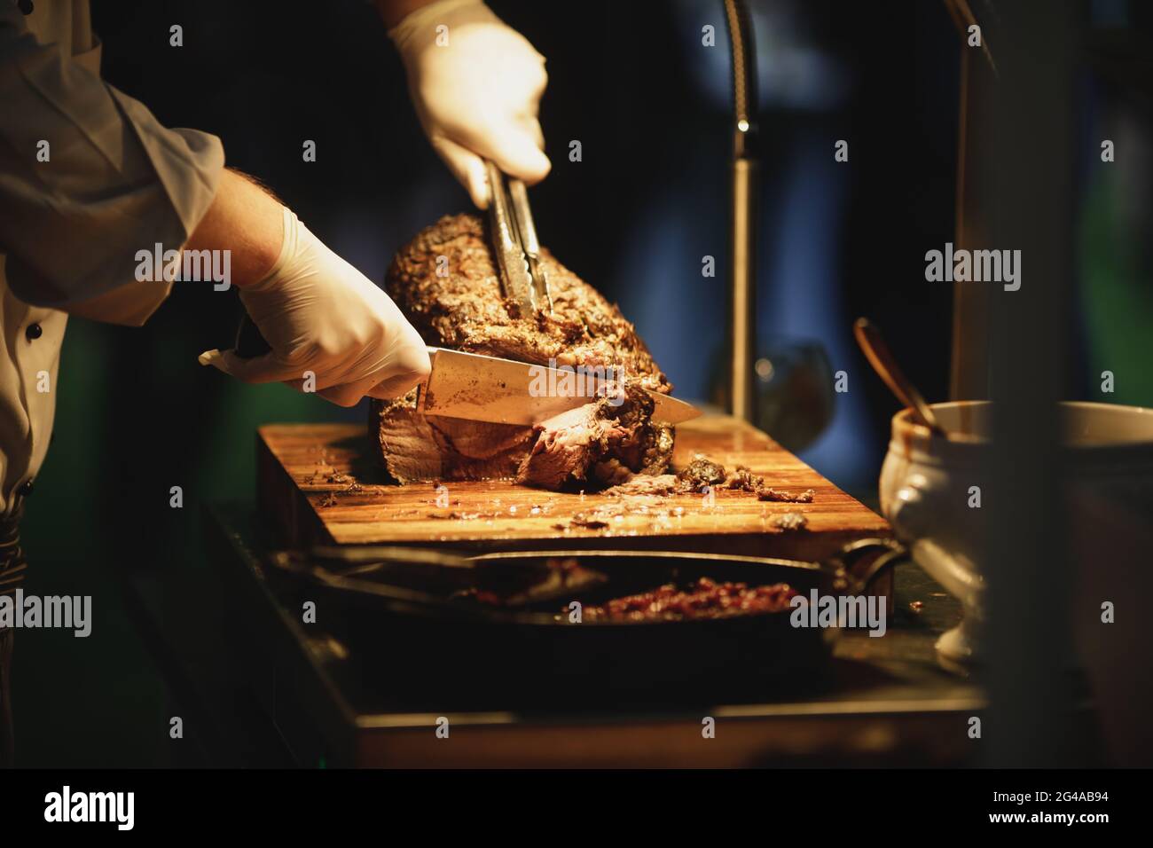 Shallow depth of field (selective focus) details with a catering chef cutting beef steak during an exclusive event. Stock Photo