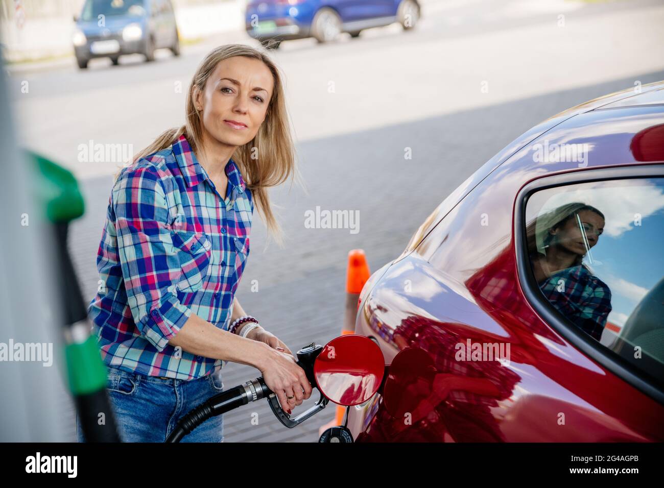 Pretty woman is filling her red car with gasoline at a gas station Stock Photo Alamy