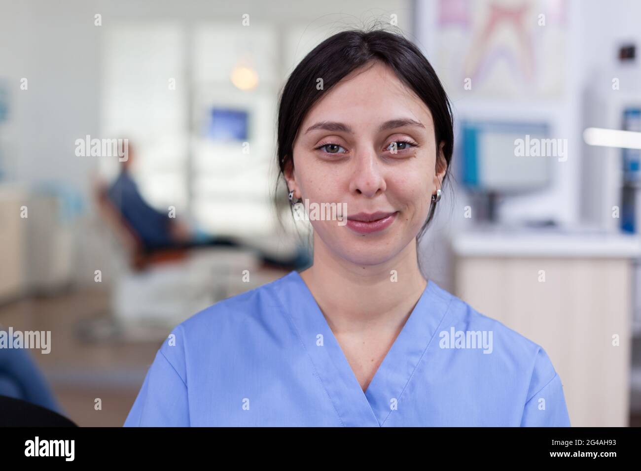 Smiling stomatology nurse looking at camera in dentist office wainting area, senior man waiting for teeth health examination. Dentistiry woman sitting on chair. Stock Photo