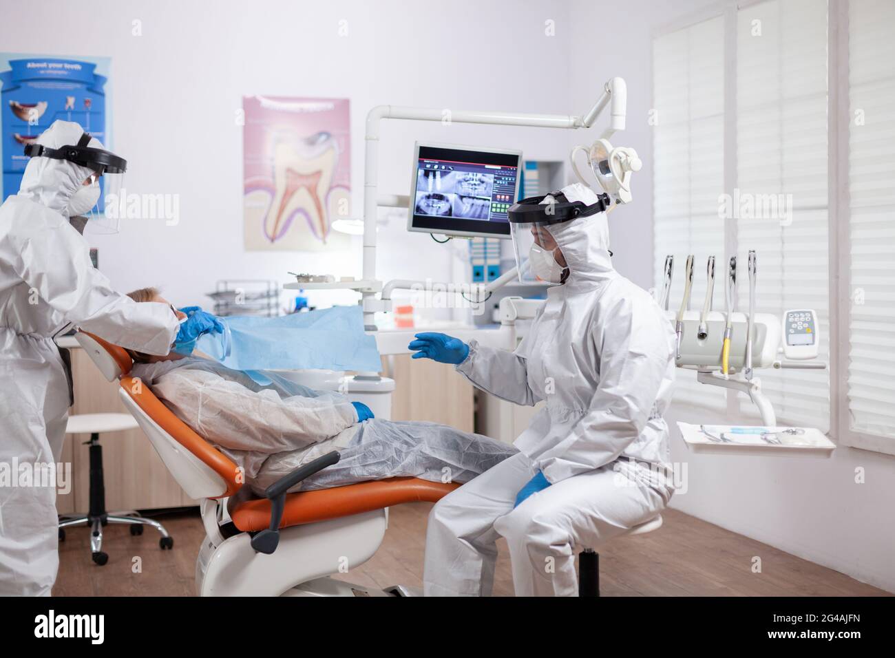 Dentist nurse taking patient temperature wearing hazmat suit using