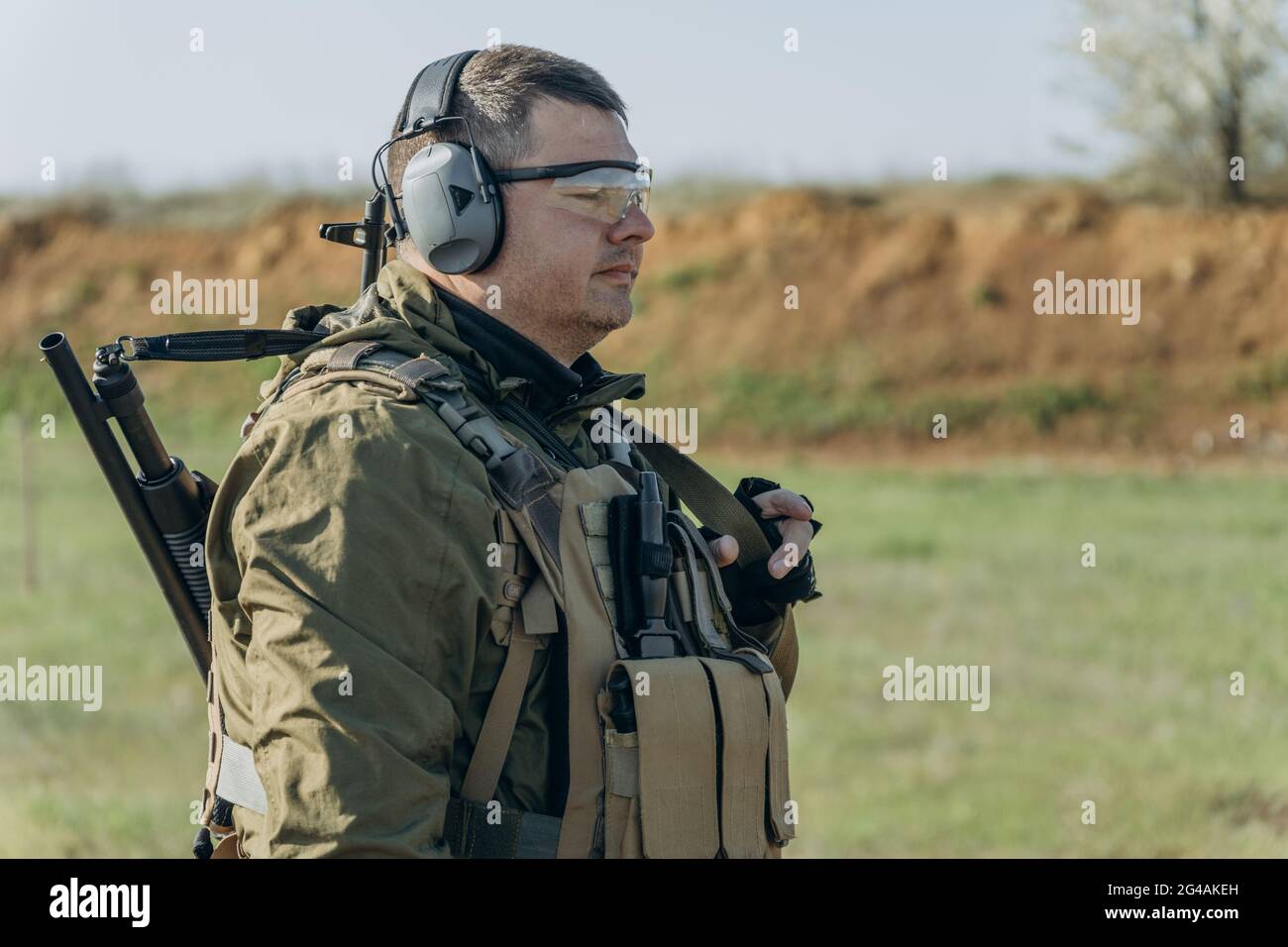 armed young white man in military uniform wearing headphones and