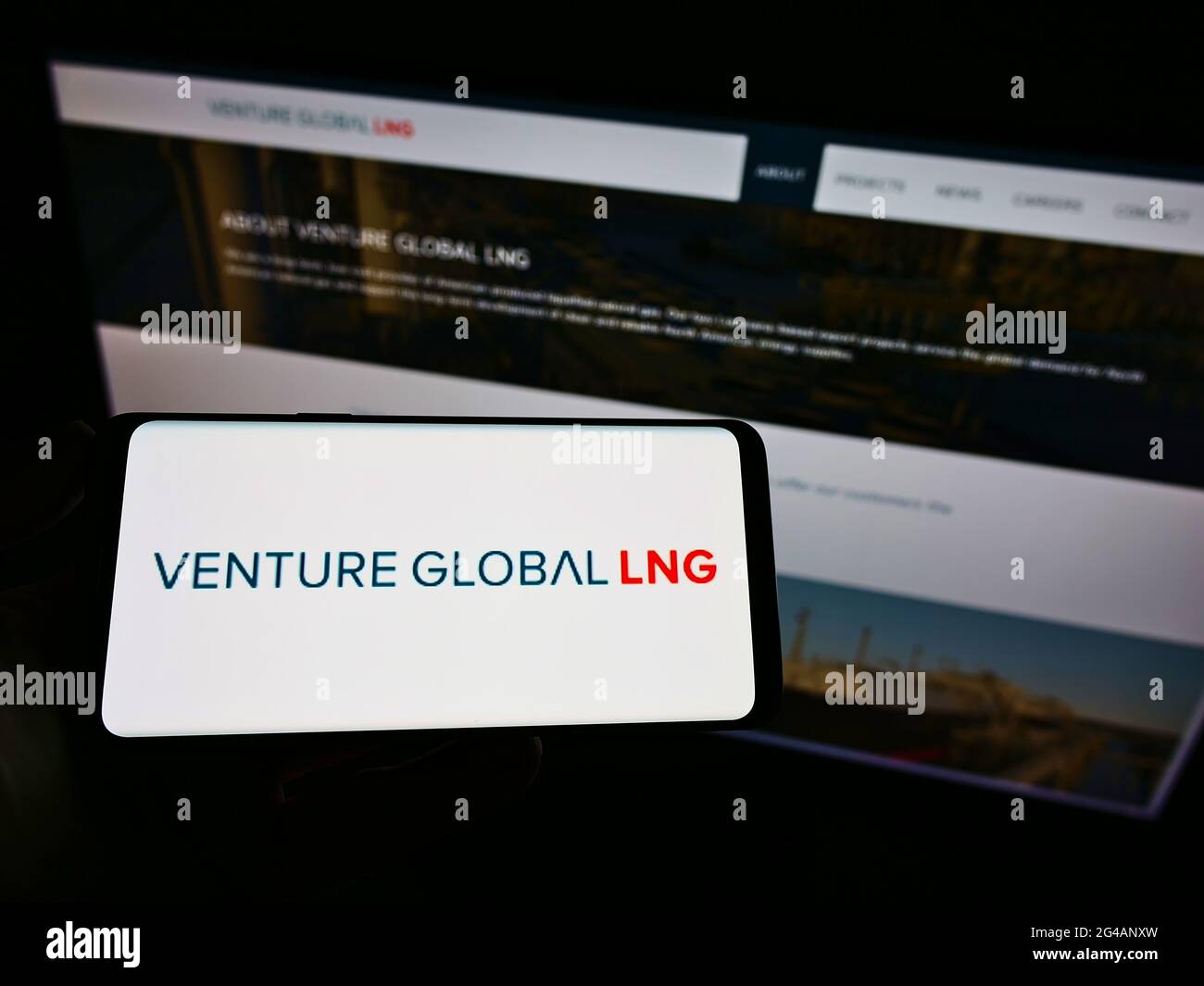 Person holding cellphone with logo of US natural gas company Venture Global LNG Inc. on screen in front of business webpage. Focus on phone display. Stock Photo