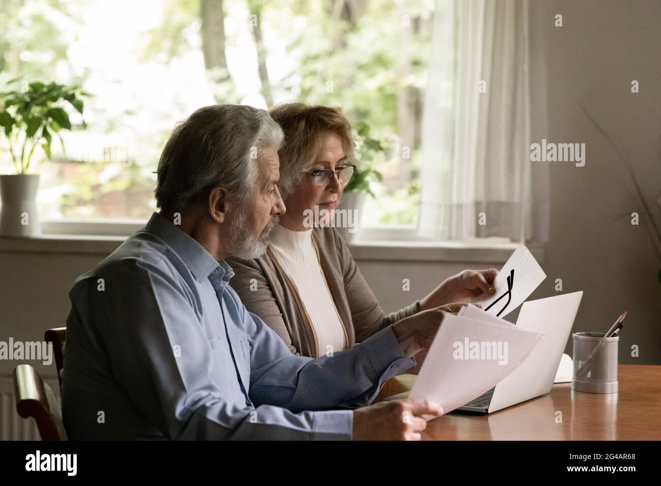 Older couple work with paperwork paying bills online Stock Photo