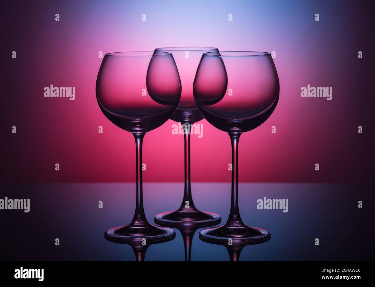 Drei leere Low Key Weinglaeser vor farbigem Hintergrund Stock Photo