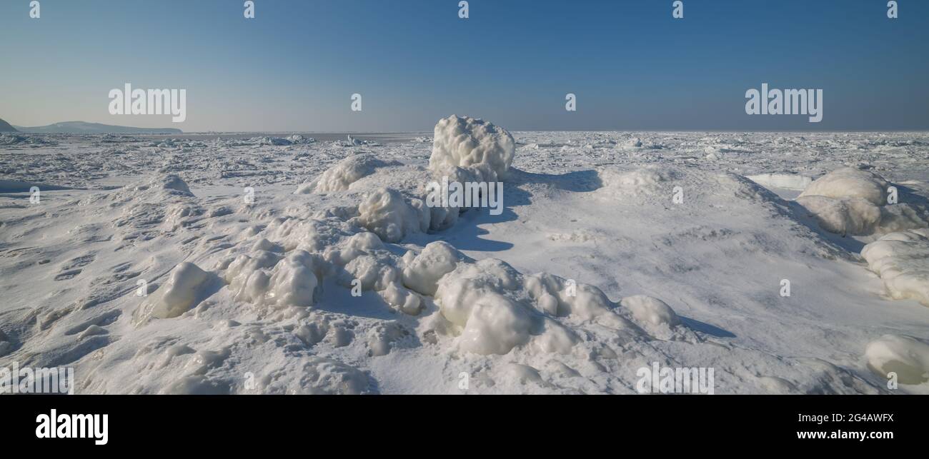 Frozen sea view on sunny day. Selective focus on ice rock. Stock Photo
