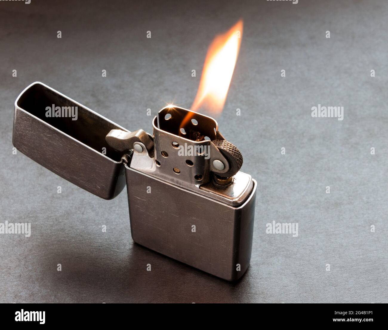 Silver metal lighter on black background with flame. Stock Photo