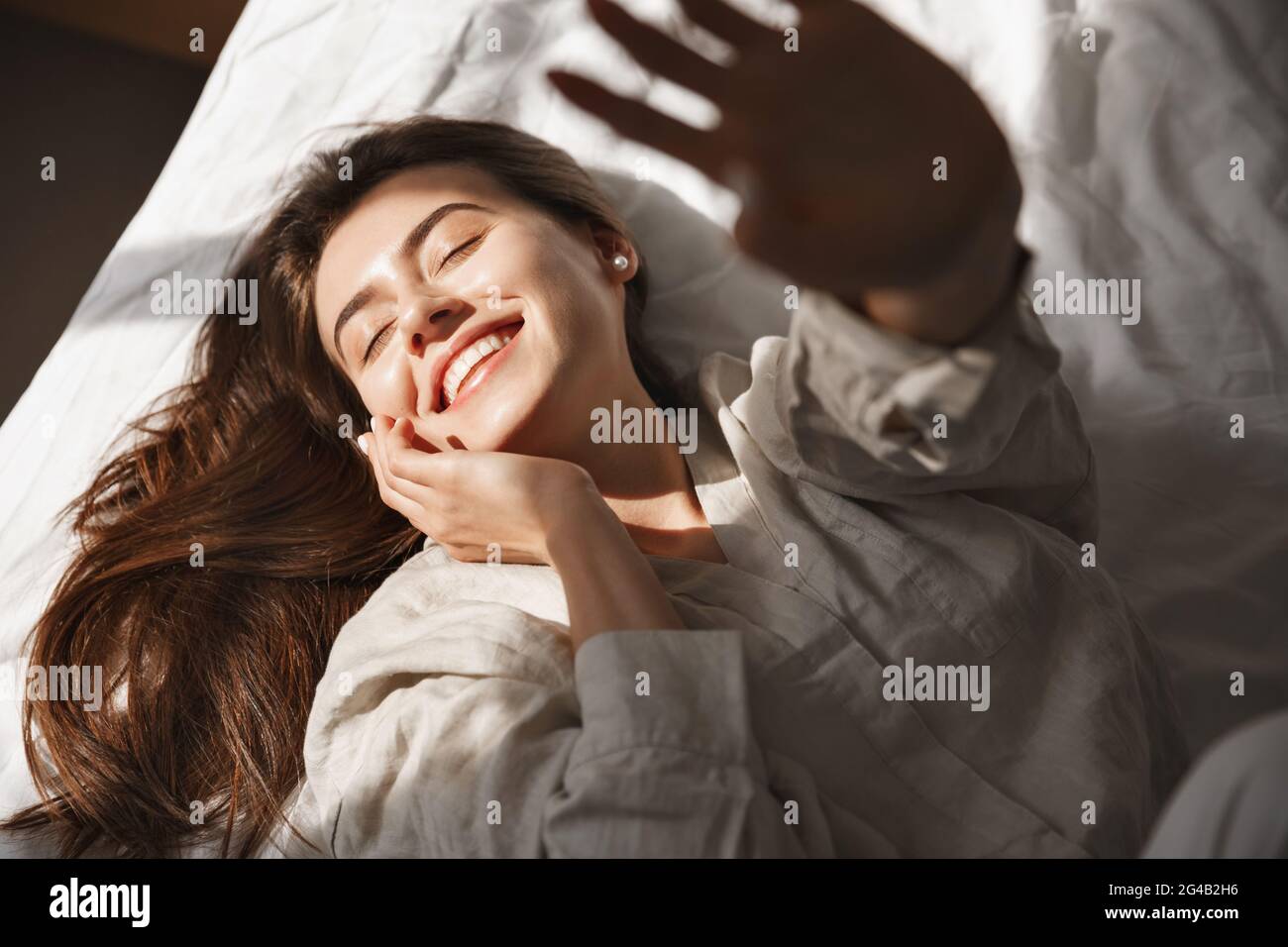 Happy Girl Waking Up Stretching Arms On The Bed In The Morning High Angle Of Young Woman Lying 