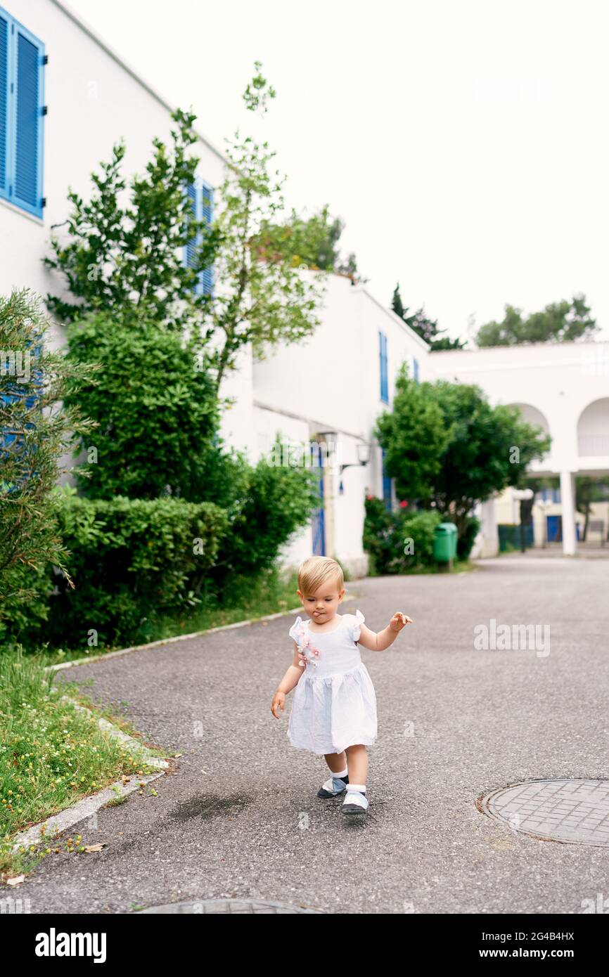 Little girl walks on the asphalt in the yard of the house Stock Photo ...