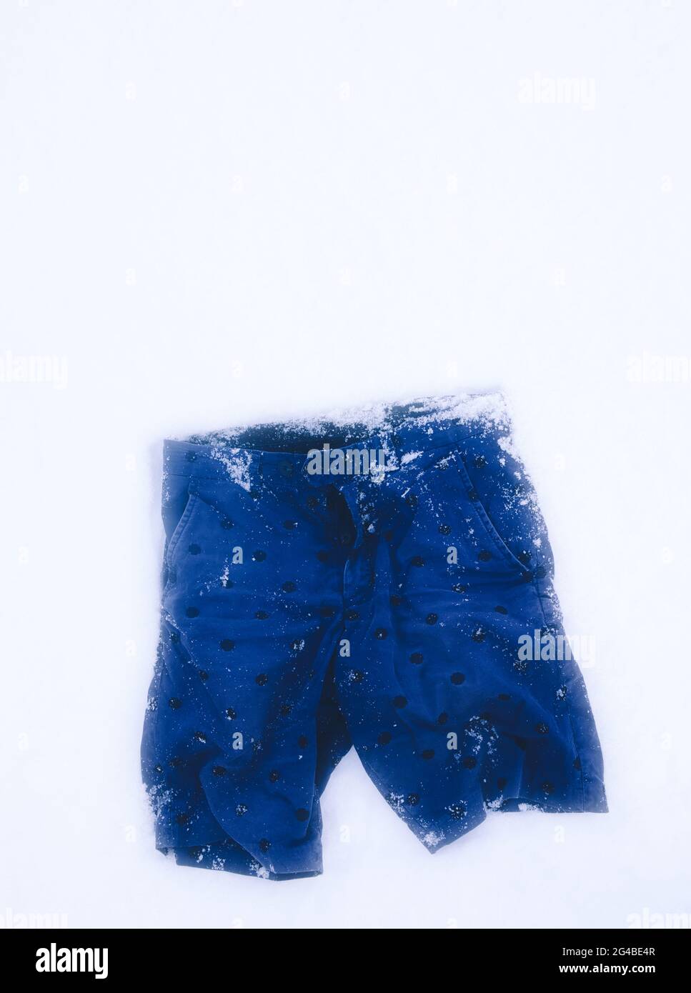 Directly above of blue shorts lying frozen in snow. Concept of abandoned, discarded Stock Photo