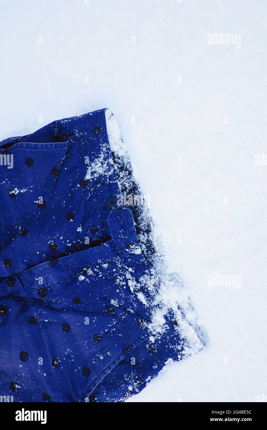 Directly above of blue shorts lying frozen in snow. Concept of abandoned, discarded Stock Photo