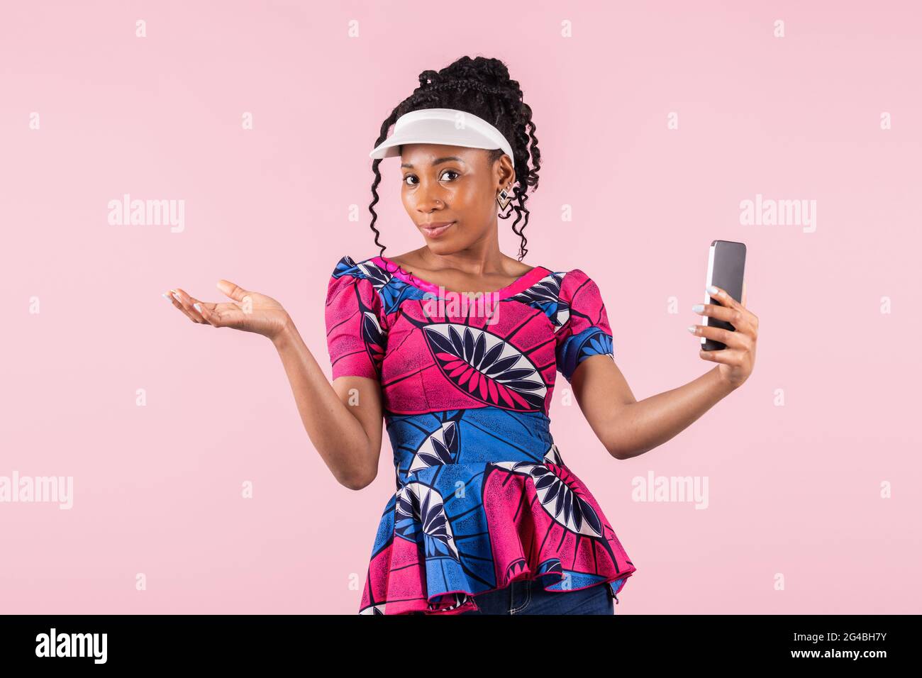 Beautiful afro american woman with visor shrugging at the camera: Technology and lifestyle concept. Stock Photo