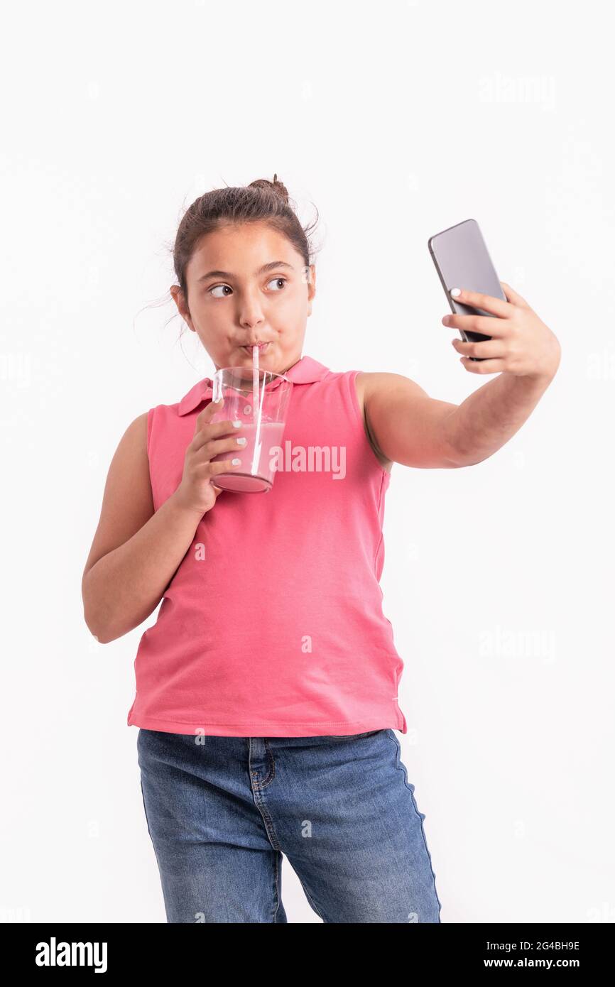 Focused little girl drinking and taking a photo of herself Stock Photo