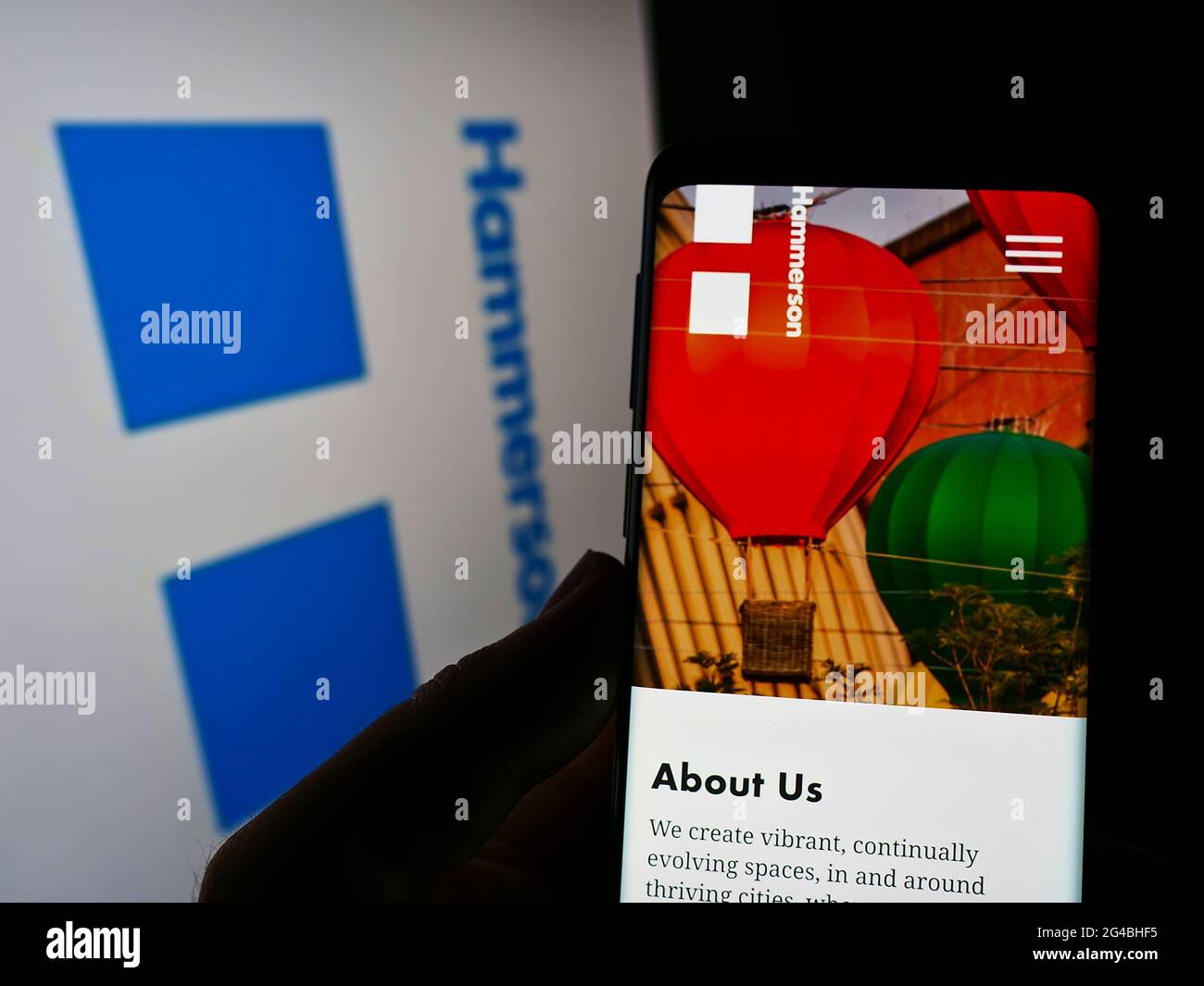 Person holding smartphone with website of British property development company Hammerson plc on screen in front of logo. Focus on phone display. Stock Photo