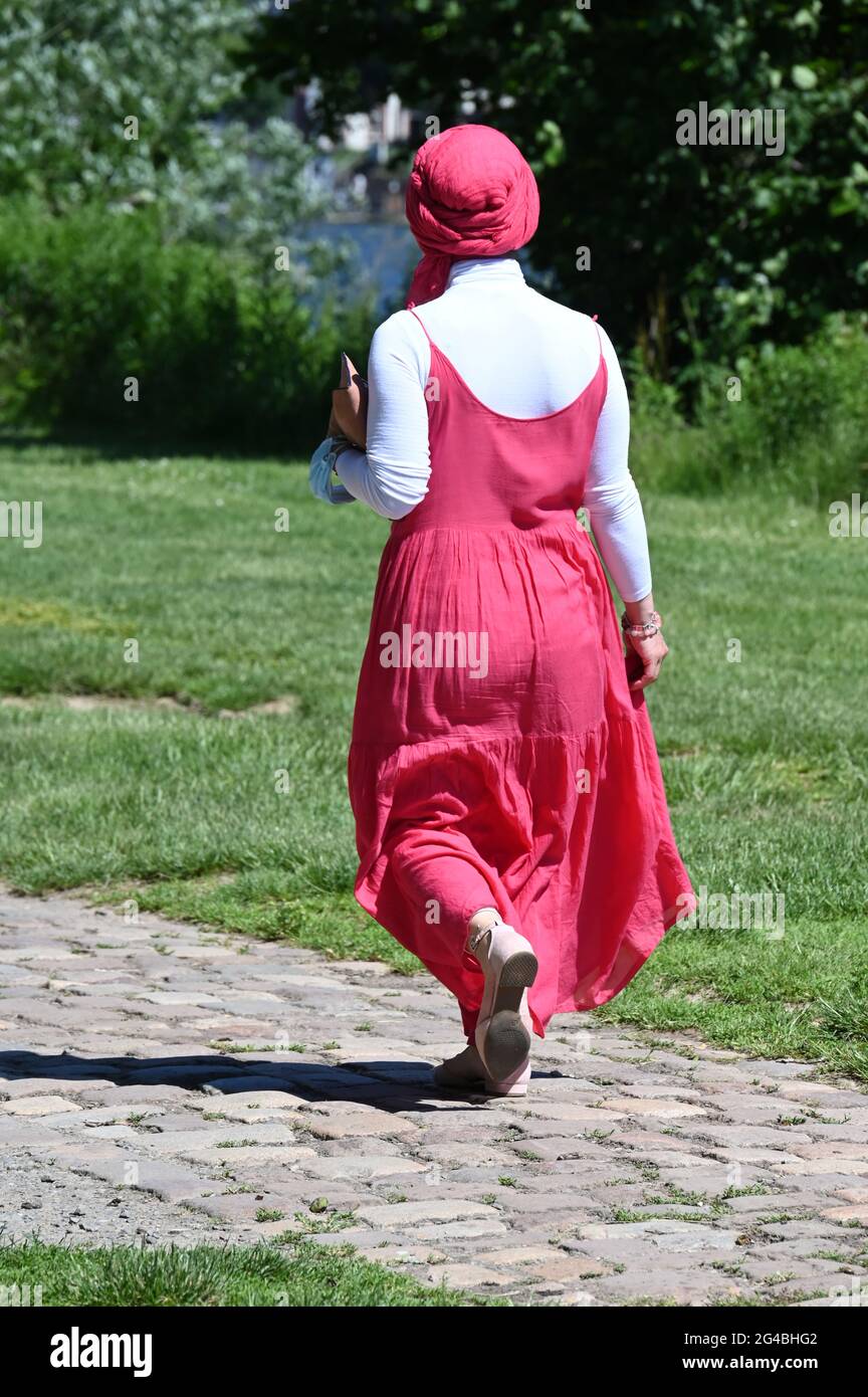 Young Muslim woman with pink headscarf and pink dress walking Stock Photo