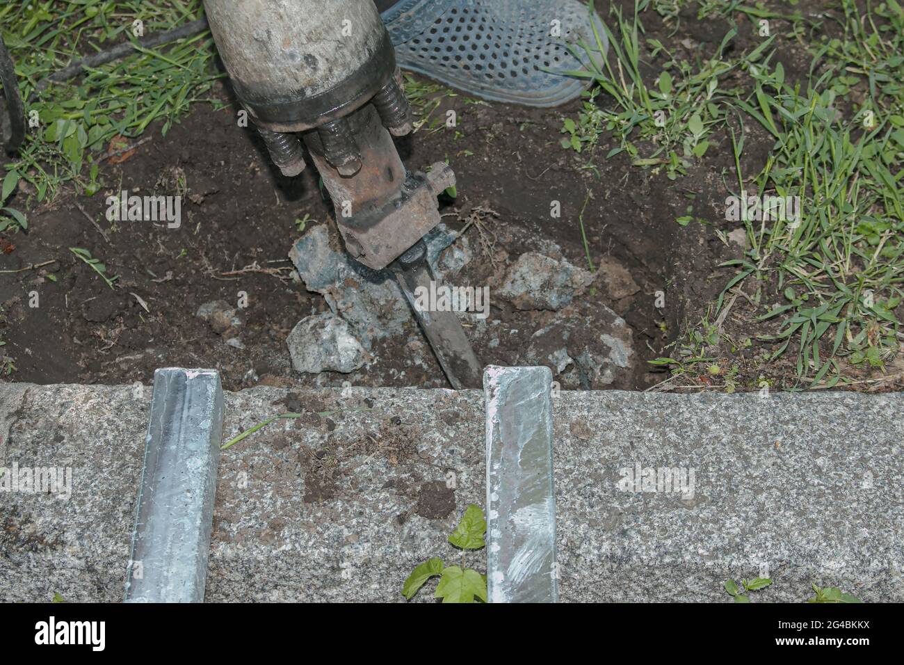 A handyman smashes an old concrete structure with an electric jackhammer. Close-up. Stock Photo