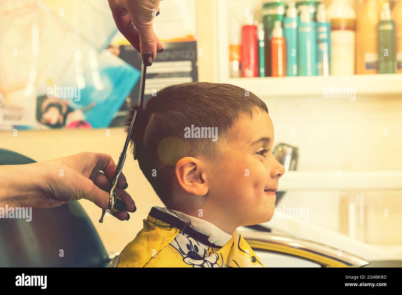 little boy having a haircut at hair salon..Children hairdresser with  scissors and comb is cutting little boy. Contented cute preschooler boy  getting Stock Photo - Alamy